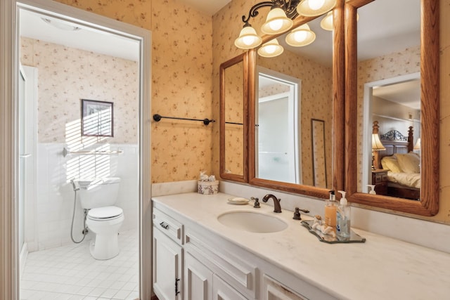 bathroom with a wainscoted wall, tile walls, toilet, vanity, and wallpapered walls