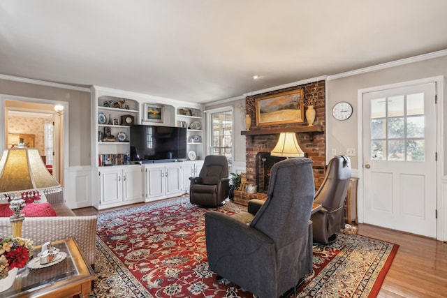 living area featuring light wood-type flooring, a fireplace, and crown molding