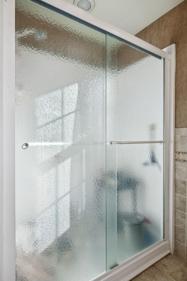 full bath with tile patterned flooring and a shower stall