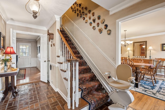 stairway with brick floor, a decorative wall, ornamental molding, wainscoting, and a chandelier