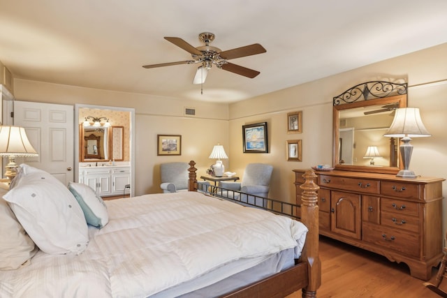 bedroom with a ceiling fan, visible vents, connected bathroom, and light wood finished floors