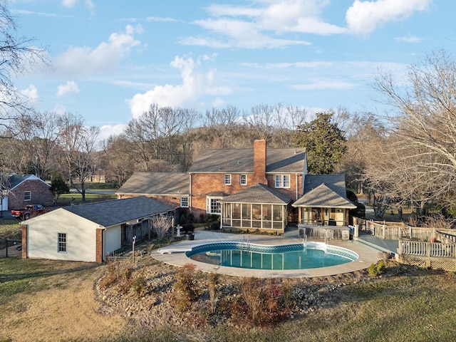 rear view of property with a fenced in pool, a patio, a chimney, a sunroom, and fence