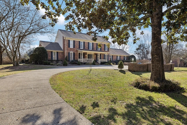 view of front of house featuring concrete driveway, brick siding, and a front lawn