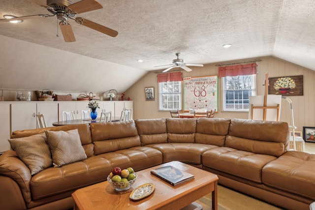 living room featuring lofted ceiling, ceiling fan, and a textured ceiling