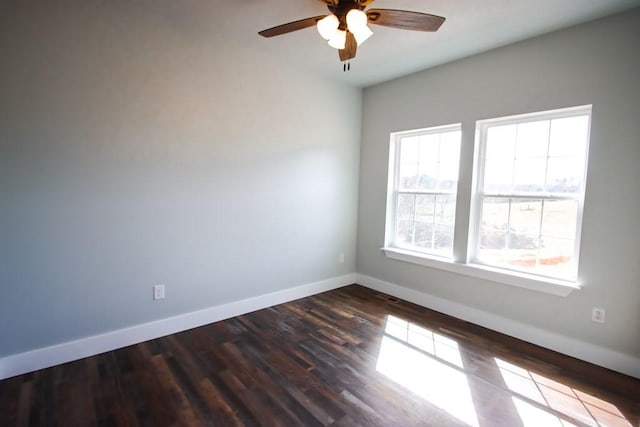 spare room featuring a ceiling fan, baseboards, and dark wood-type flooring