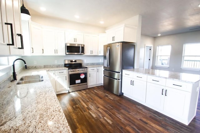 kitchen featuring light stone counters, a sink, white cabinets, appliances with stainless steel finishes, and dark wood finished floors