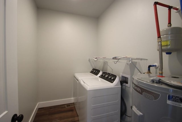 washroom with laundry area, wood finished floors, baseboards, water heater, and washer and dryer