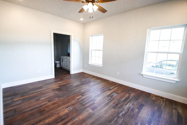 spare room with a ceiling fan, baseboards, visible vents, and dark wood-style flooring