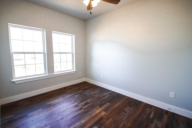 unfurnished room featuring a ceiling fan, visible vents, dark wood finished floors, and baseboards