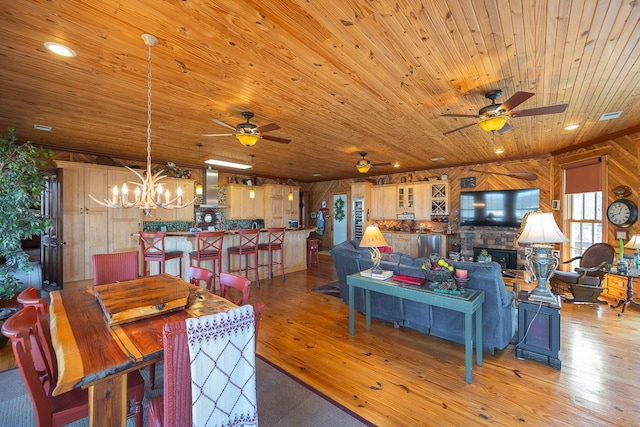 dining area featuring recessed lighting, light wood-style floors, wood ceiling, and a stone fireplace