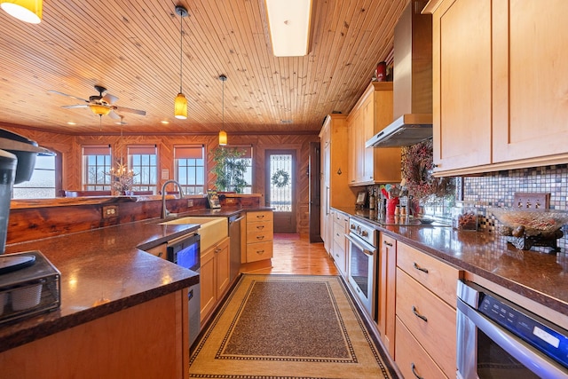 kitchen with pendant lighting, stainless steel appliances, a sink, wall chimney range hood, and wooden ceiling