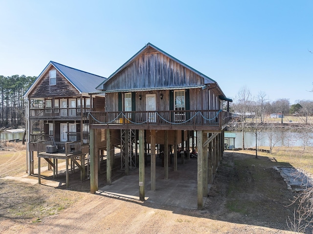 back of property with dirt driveway, a carport, and a water view