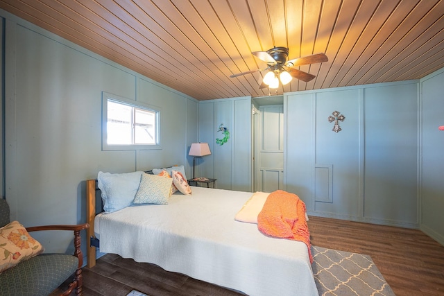 bedroom featuring wooden ceiling, wood finished floors, and a decorative wall