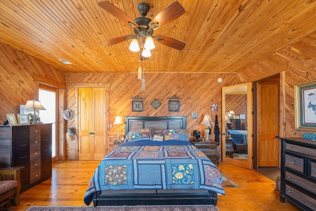 bedroom with ceiling fan, wood finished floors, wood ceiling, and wooden walls