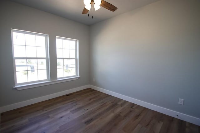 spare room with ceiling fan, dark wood-type flooring, visible vents, and baseboards