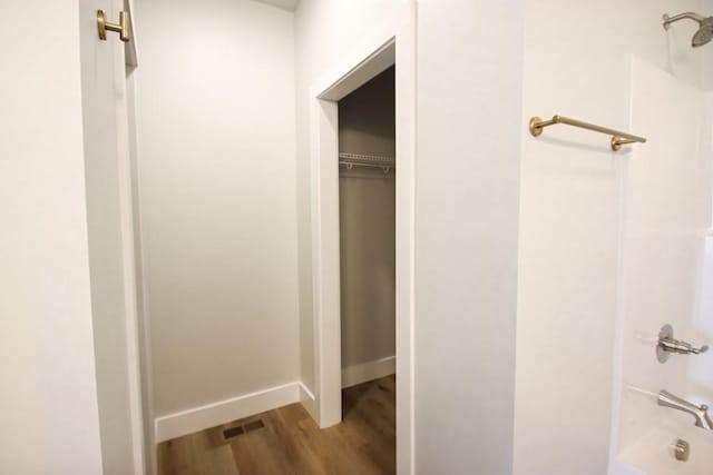 bathroom with shower / bath combination, baseboards, visible vents, and wood finished floors