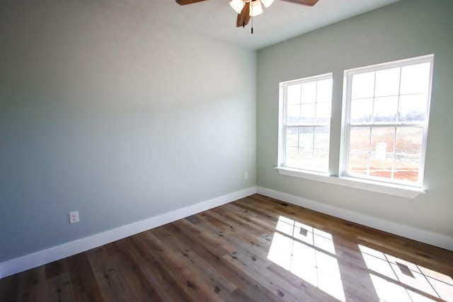 empty room with wood finished floors, a ceiling fan, and baseboards