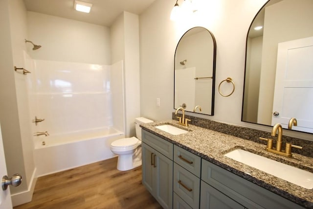 bathroom featuring wood finished floors, shower / bath combination, a sink, and toilet