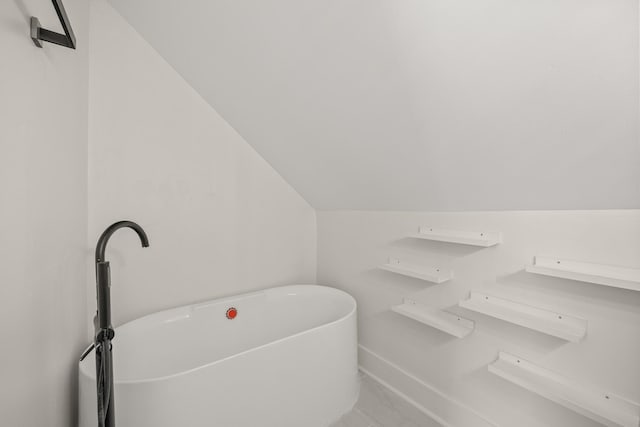 full bath with lofted ceiling and a freestanding tub