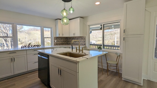 kitchen featuring tasteful backsplash, dishwasher, dark wood-type flooring, decorative light fixtures, and a sink