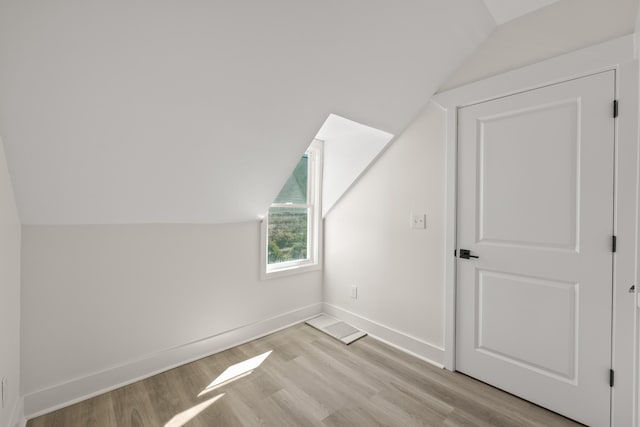 bonus room featuring lofted ceiling, light wood-style flooring, and baseboards