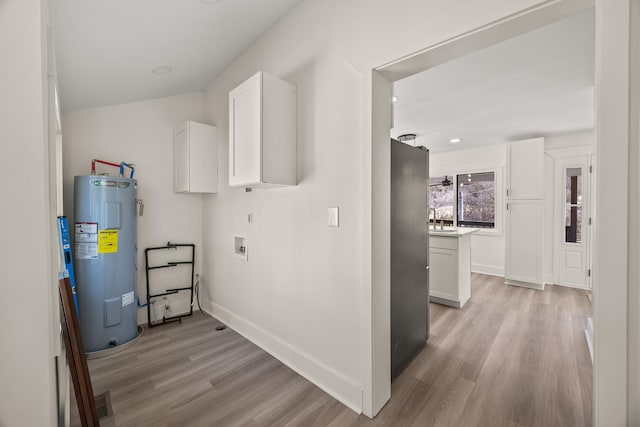 washroom with baseboards, electric water heater, hookup for a washing machine, light wood-style floors, and a sink