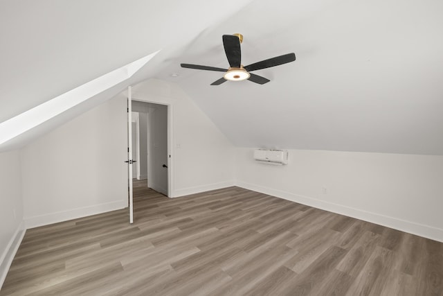 bonus room featuring light wood-style floors, vaulted ceiling with skylight, and baseboards