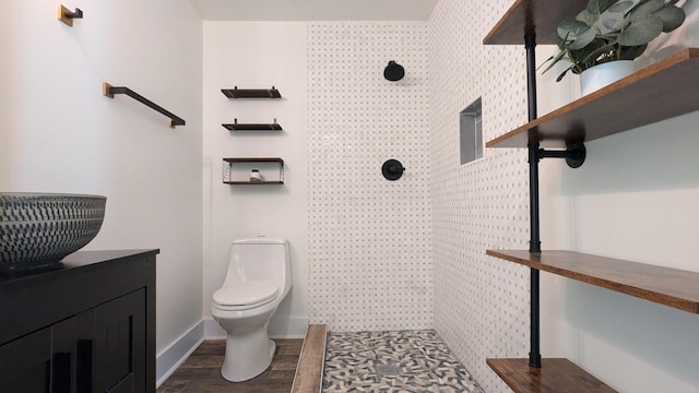 bathroom featuring toilet, a tile shower, wood finished floors, and vanity