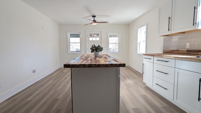 kitchen featuring butcher block counters, a healthy amount of sunlight, light wood finished floors, and decorative backsplash