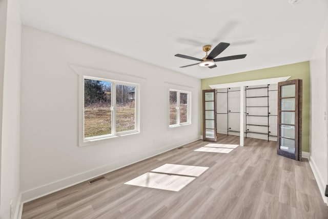 unfurnished bedroom featuring a ceiling fan, visible vents, light wood-style flooring, and baseboards