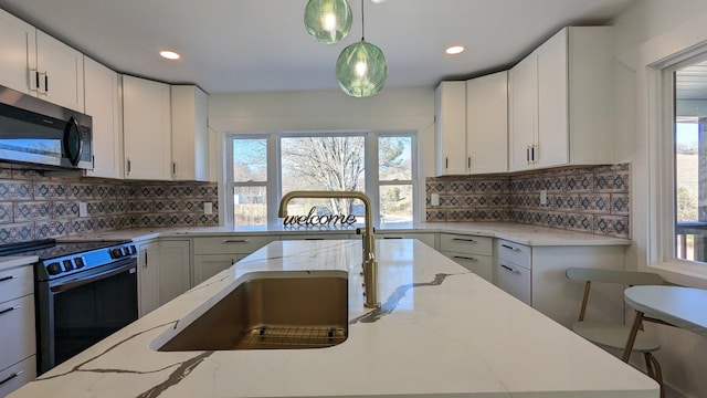 kitchen featuring electric range, stainless steel microwave, light stone counters, and decorative light fixtures