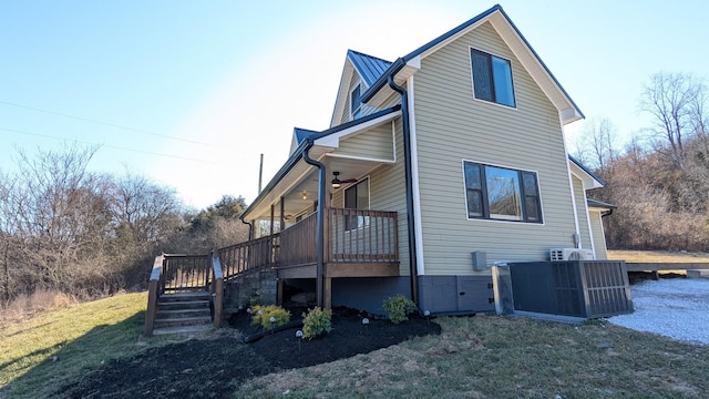 view of side of property with a lawn, metal roof, a deck, and stairs