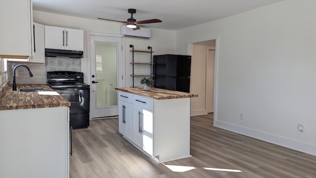 kitchen with under cabinet range hood, black appliances, wooden counters, a sink, and a wall mounted AC