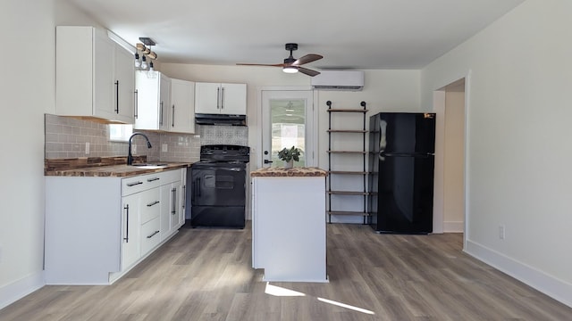 kitchen featuring a wall mounted AC, white cabinetry, a sink, ventilation hood, and black appliances