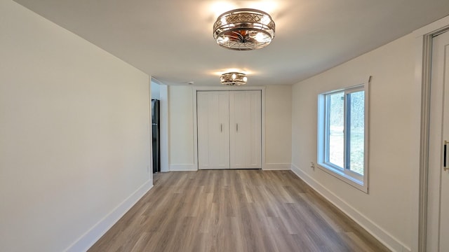 interior space featuring a closet, light wood-style flooring, and baseboards