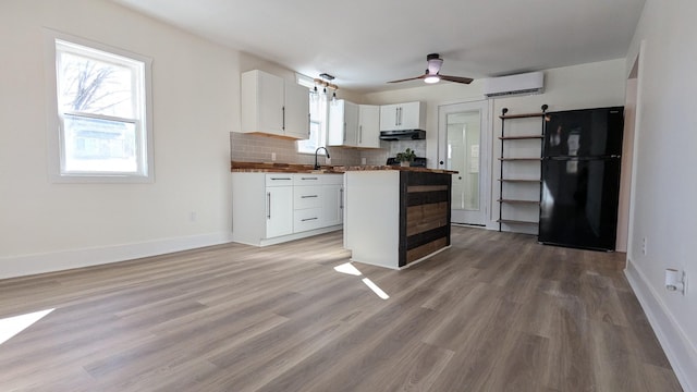 kitchen with open shelves, freestanding refrigerator, an AC wall unit, white cabinets, and a sink