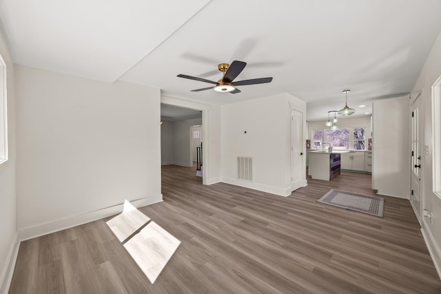 unfurnished living room featuring baseboards, visible vents, and wood finished floors