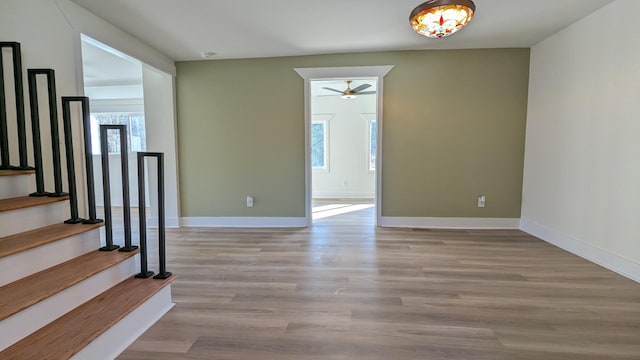 interior space with a ceiling fan, stairway, baseboards, and wood finished floors