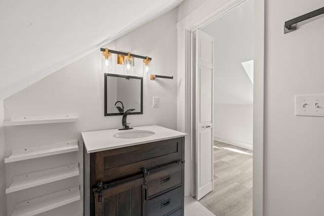 bathroom featuring vaulted ceiling, wood finished floors, and vanity