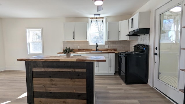 kitchen with black / electric stove, under cabinet range hood, butcher block counters, a sink, and white cabinets