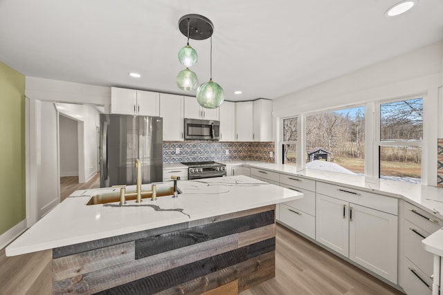 kitchen with appliances with stainless steel finishes, light wood-style floors, white cabinets, and decorative backsplash