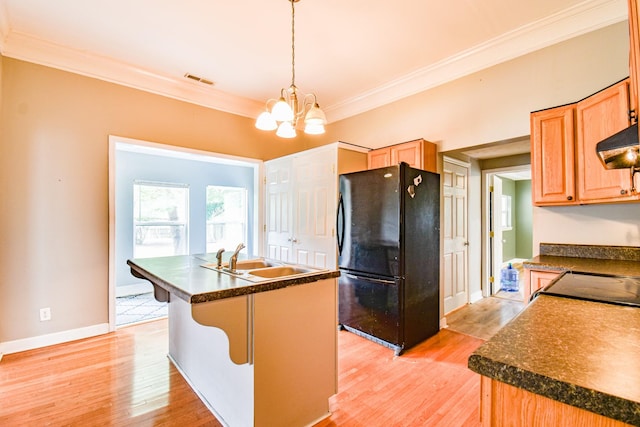 kitchen featuring light wood finished floors, dark countertops, ornamental molding, freestanding refrigerator, and a sink