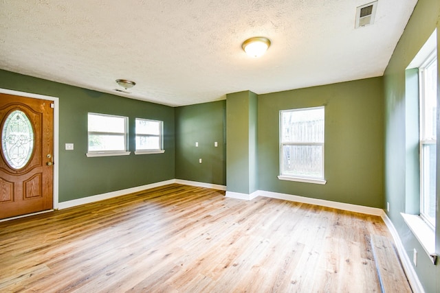 foyer entrance with baseboards, visible vents, and wood finished floors