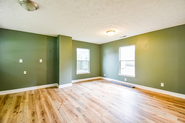 unfurnished room featuring light wood finished floors, plenty of natural light, visible vents, and baseboards