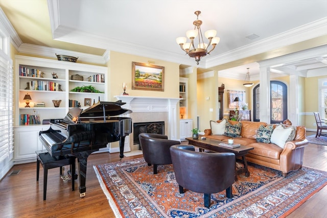 interior space featuring built in shelves, a notable chandelier, wood finished floors, a high end fireplace, and crown molding