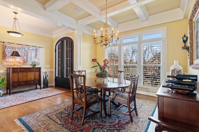 dining room with arched walkways, beam ceiling, coffered ceiling, and wood finished floors