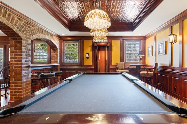 game room with ornamental molding, a raised ceiling, a healthy amount of sunlight, and a notable chandelier