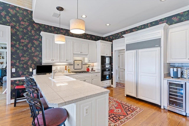 kitchen featuring beverage cooler, a breakfast bar area, a sink, and wallpapered walls