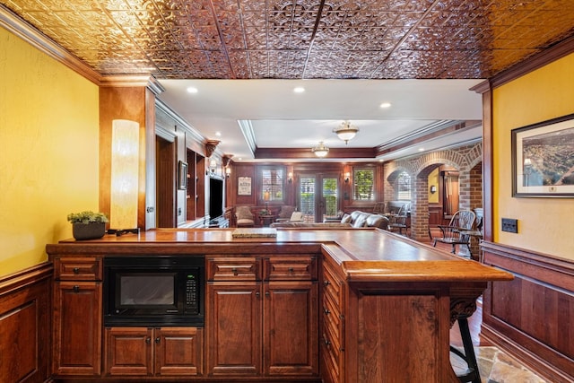 kitchen featuring an ornate ceiling, black microwave, wainscoting, and crown molding