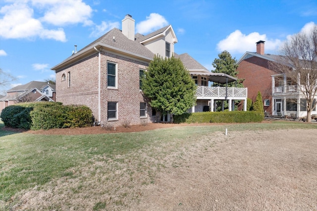 back of property featuring a yard, brick siding, and a chimney